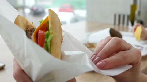 Open paper packaging and eat fresh juicy sandwich at a fast food restaurant Stock-Footage 60141330