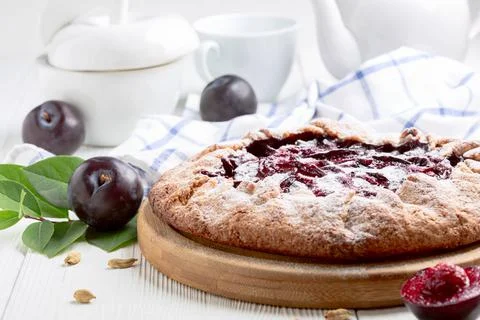 Open pie or galette with red plums and cardamom. Stock Photos