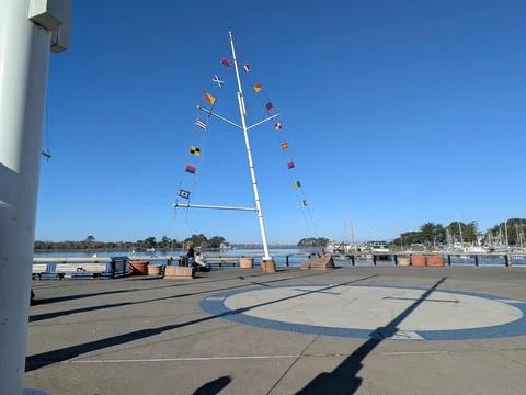 Open pier with compass design on ground, boats across bay Fotos Stock