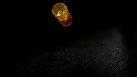 Open pill bottle falling on the black surface in slow motion Видео 81230325