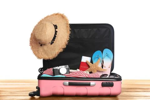Open pink suitcase with different beach objects on wooden table, white backgr Stock Photos
