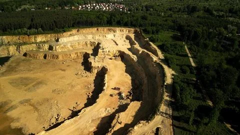 Open-Pit Dolomite Quarry with Working Trucks and Residential Area in the Backgro Stock Photos