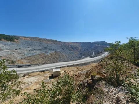 Open pit mining quarry with terraced slopes and clear blue sky 스톡 사진