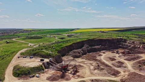 Open pit mining site with machinery and green fields in the background Stock-Footage 338240923