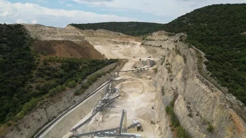 Open-pit quarry with heavy machinery transporting stone in a hillside mining Stock Footage 314337393