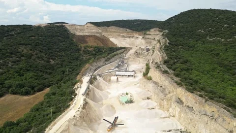 Open-pit quarry with heavy machinery transporting stone in a hillside mining Stock Footage 314337418