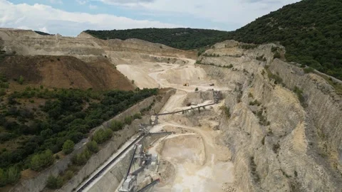 Open-pit quarry with heavy machinery transporting stone in a hillside mining Stock Footage 314337419