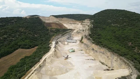 Open-pit quarry with heavy machinery transporting stone in a hillside mining Stock Footage 314337828