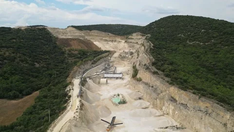 Open-pit quarry with heavy machinery transporting stone in a hillside mining Stock Footage 314338009
