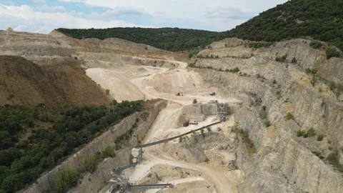 Open-pit quarry with heavy machinery transporting stone in a hillside mining Stock Footage 314338213