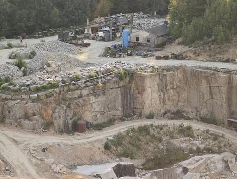 Open pit quarry industrial mining worksite featuring rocky cliff face, gravel Stock Photos