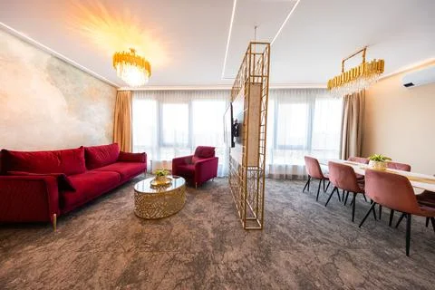 Open plan living and dining room with ruby seating and gold accents Stock Photos