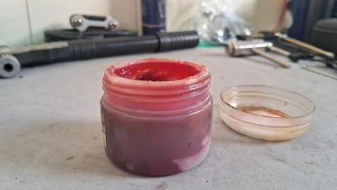 Open plastic container filled with thick red industrial lubricating grease Stock Photos