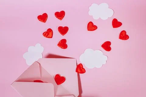 An open postal envelope with red hearts and clouds flying out of it. Hearts Stock Photos
