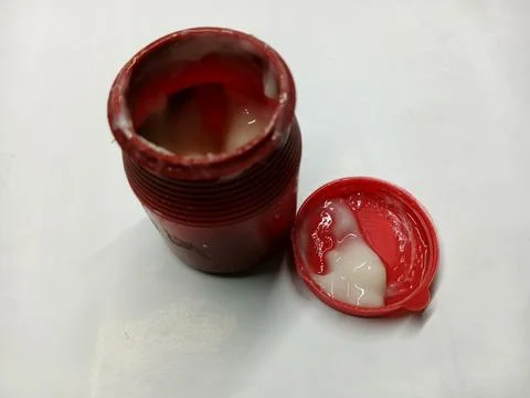 Open red plastic container of white stationary paper glue with cap aside Stock Photos