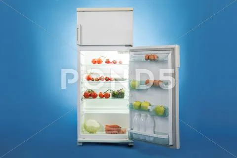 Open refrigerator full of healthy food isolated over blue background Stock-Fotos