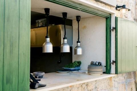 Open Restaurant Serving Window with Kitchen Counter and Hanging Heat Lamps Stock Photos