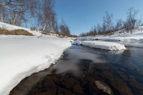 Open river at spring with snow and trees Stock Photos