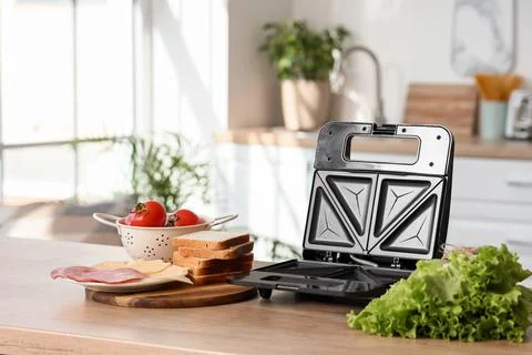Open sandwich maker with bread, cheese, ham, tomatoes, and lettuce on a woode Stock Photos