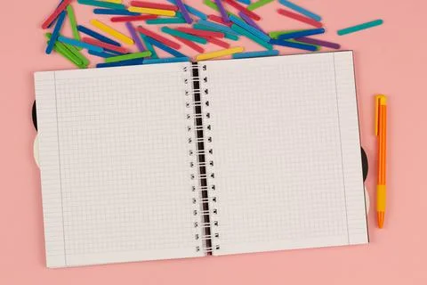 Open school squared notebook and colored rulers on the pink background. Top view Stock Photos