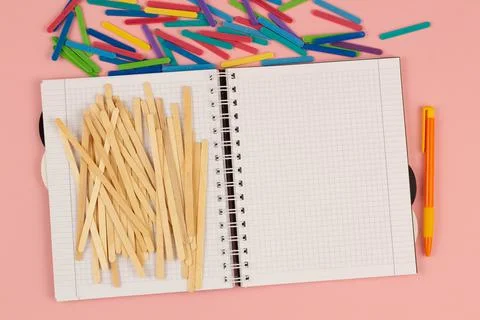 Open school squared notebook and colored rulers on the pink background. Top view Stock Photos