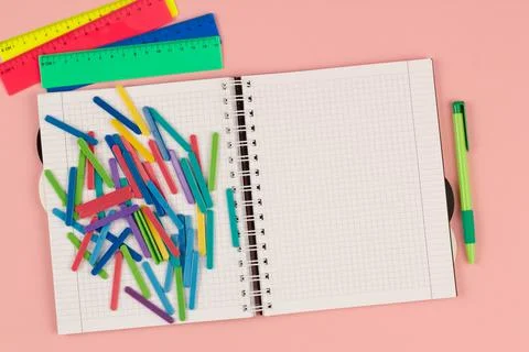 Open school squared notebook and colored rulers on the pink background. Top view Stock Photos
