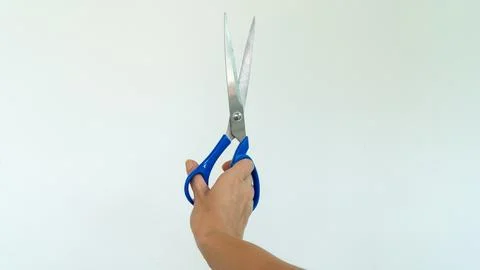 Open scissors in right hand on white background Stock Photos
