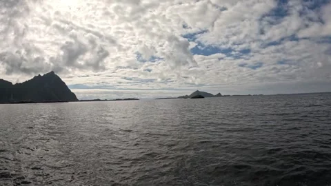 Open sea boat navigation with mountain peak silhouette and cloudy sky Lofoten 库存影片 344047433