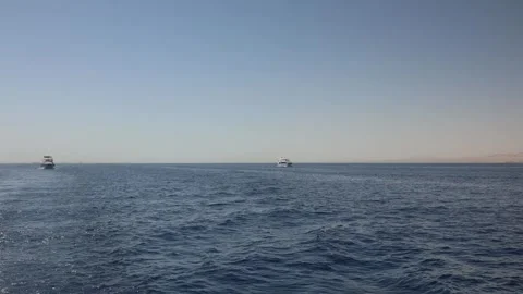 Open sea calm horizon distant yachts gentle waves desert coastline soft haze pea Stock Footage 310820070