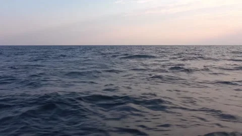 The open sea at sunset or dawn. Pitching in ocean. Dolphins jump out frome water Stock Footage 130438933