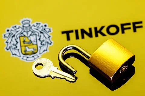 An open security lock and key on background of Tinkoff bank logo Stock Photos