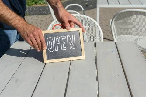 Open sign on cafe table in hands of waiter Stock Photos