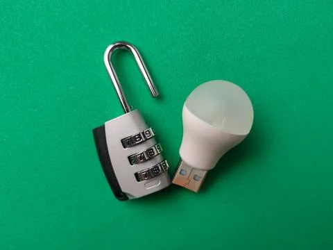 An open silver combination padlock rests next to a white USB-powered LED li.. Stock Photos