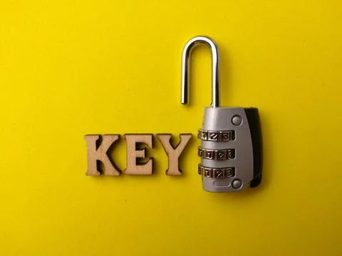 An open silver combination padlock rests next to the wooden letters spellin.. 스톡 사진