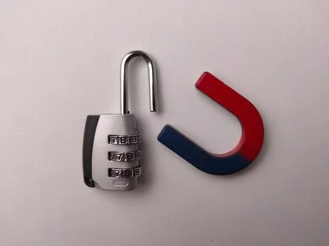 An open silver combination padlock sits next to a red and blue horseshoe ma.. Stock Photos