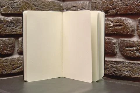 Open sketchbook is on the table. background brick wall Stock Photos