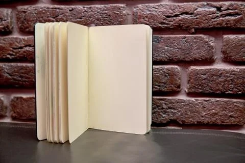 Open sketchbook is on the table. background brick wall Stock Photos
