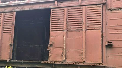 Open sliding door of old rusty red metal freight train car revealing dark e.. Stock Photos