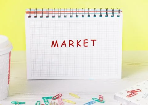 An open, spiral-bound notebook sits on a desk with colorful paperclips scattered Stock Photos