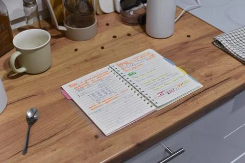 Open spiral notebook with Russian notes on wooden kitchen countertop Foto stock