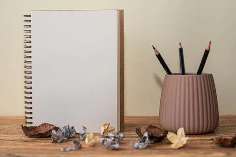 Open spiral notebook with white sheet, pencils in the glass next to it and de Stock Photos