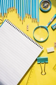 Open spiral notebook on yellow background with school tools. Education flat lay Stock Photos