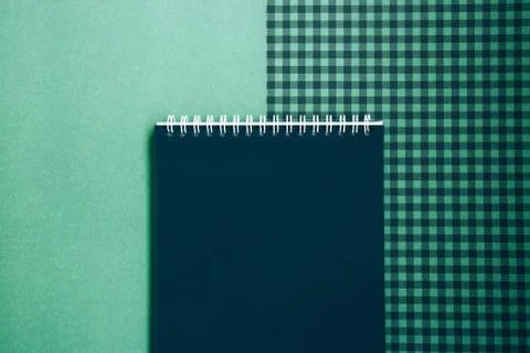 Open spiral notepad with black pages on a green checkered background Stock Photos