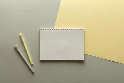 Open spiral notepad on gray and yellow background Stock Photos