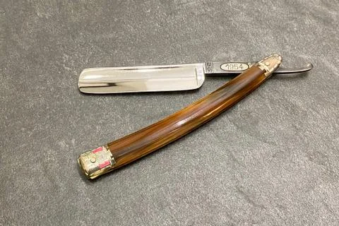 Open straight razor on a gray background with free space on the right Stock Photos