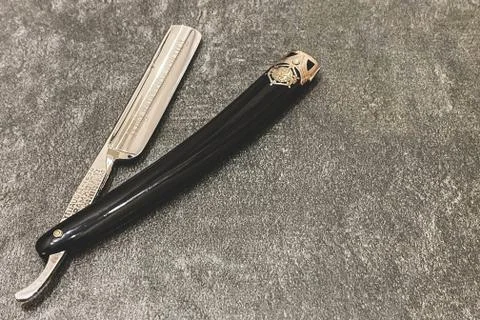 Open straight razor on a gray background with free space on the right Stock Photos