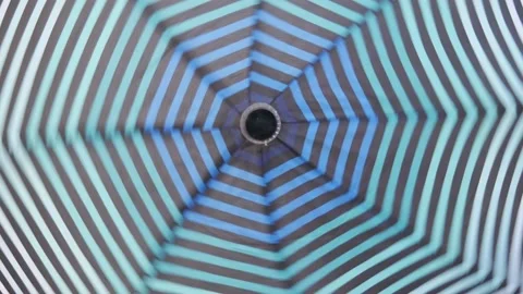 An open striped umbrella spinning around its axis. Stock Footage 141980098