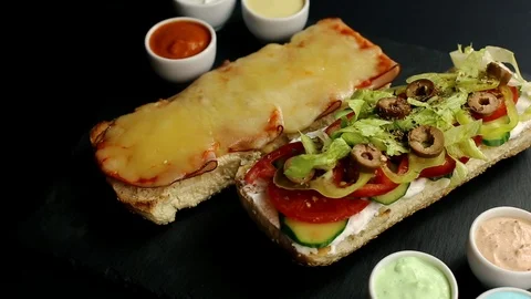 Open sub sandwich with ham, cheese, tomatoes, lettuce, cucumbers and sauces Stock Footage 93656373