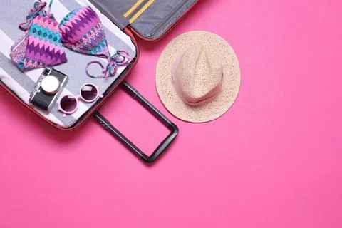 Open suitcase and beach objects on pink background, flat lay. Space for text Stock Photos