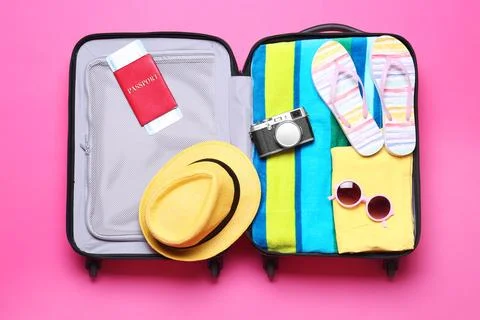 Open suitcase with beach objects on pink background, top view Stock Photos